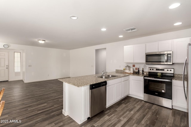 kitchen with stainless steel appliances, a peninsula, a sink, and white cabinets