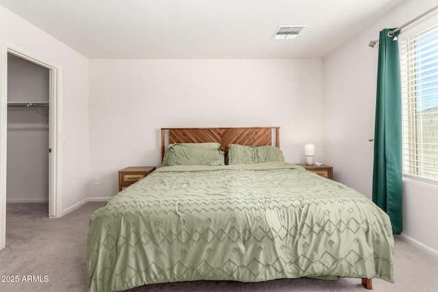 bedroom featuring visible vents, light carpet, baseboards, and a spacious closet