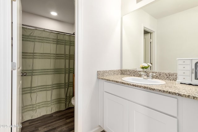 bathroom with a shower with shower curtain, toilet, wood finished floors, vanity, and recessed lighting