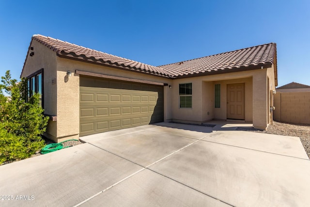 mediterranean / spanish-style home with a garage, a tile roof, concrete driveway, and stucco siding