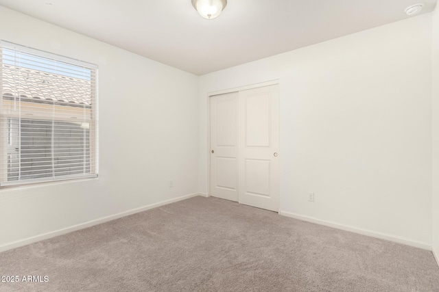 unfurnished bedroom with a closet, carpet flooring, and baseboards