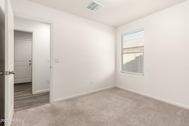 spare room with baseboards, visible vents, and light colored carpet