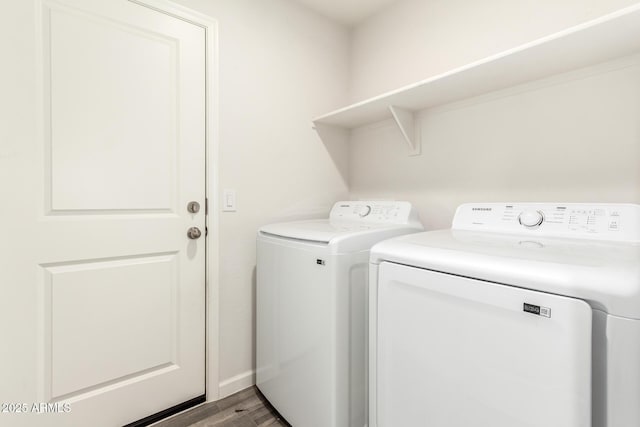 clothes washing area with laundry area, washer and dryer, and wood finished floors