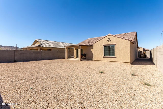 back of house with a tile roof, a patio, a fenced backyard, and stucco siding