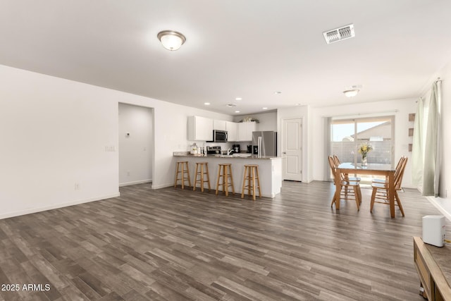 living room featuring dark wood-style floors, recessed lighting, visible vents, and baseboards