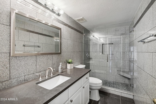 bathroom with vanity, decorative backsplash, a textured ceiling, tile walls, and walk in shower