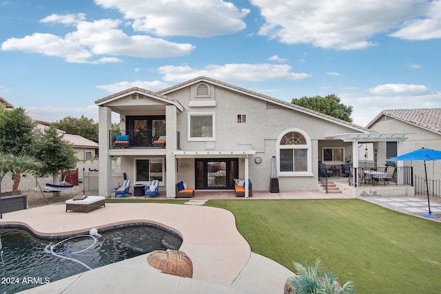 rear view of house featuring a patio, a balcony, and a lawn