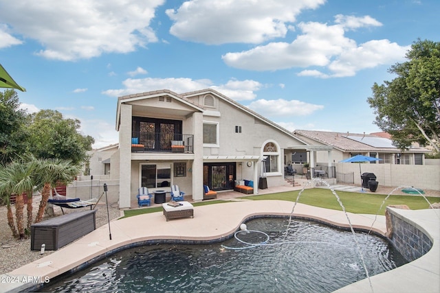 back of house featuring a patio, a balcony, pool water feature, and a fenced in pool