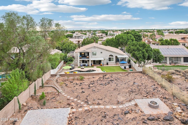 exterior space featuring a lawn, a patio area, a balcony, and an outdoor fire pit