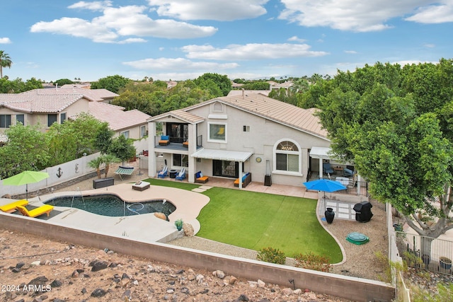 back of house with a yard, a balcony, a patio, and a fenced in pool