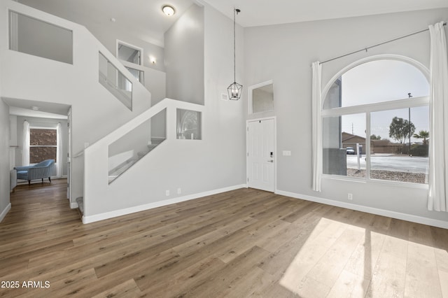 entrance foyer featuring high vaulted ceiling, plenty of natural light, stairway, and wood finished floors