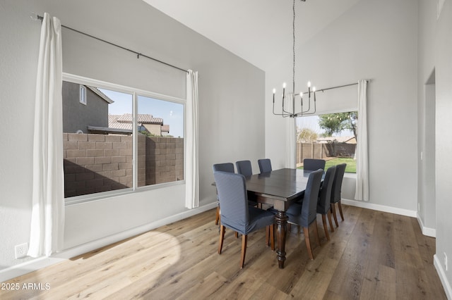 dining room with baseboards, a healthy amount of sunlight, wood finished floors, and an inviting chandelier