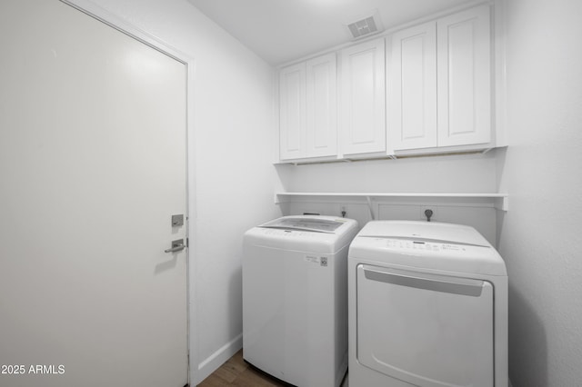 washroom with dark wood-style floors, cabinet space, visible vents, independent washer and dryer, and baseboards