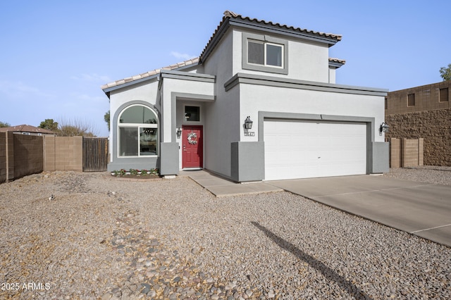 mediterranean / spanish home featuring driveway, fence, a tiled roof, and stucco siding