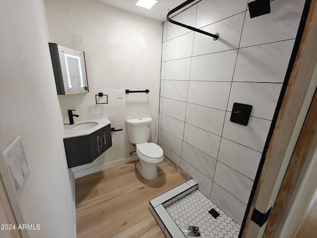 bathroom featuring a shower, toilet, vanity, tile walls, and hardwood / wood-style flooring