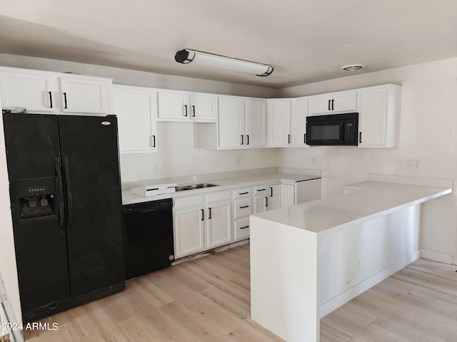 kitchen with kitchen peninsula, white cabinetry, light hardwood / wood-style flooring, and black appliances