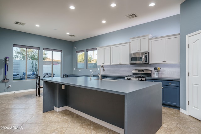 kitchen featuring a center island with sink, stainless steel appliances, light tile patterned floors, sink, and white cabinets