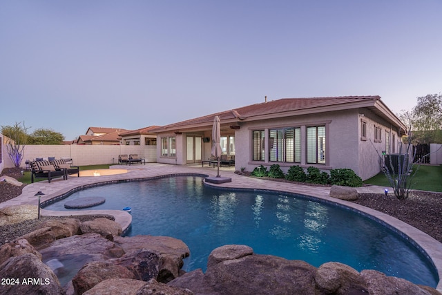 pool at dusk with a patio area