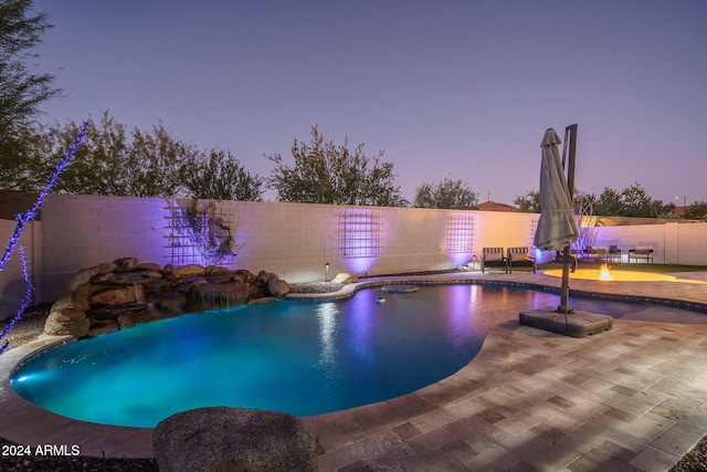 pool at dusk featuring a patio