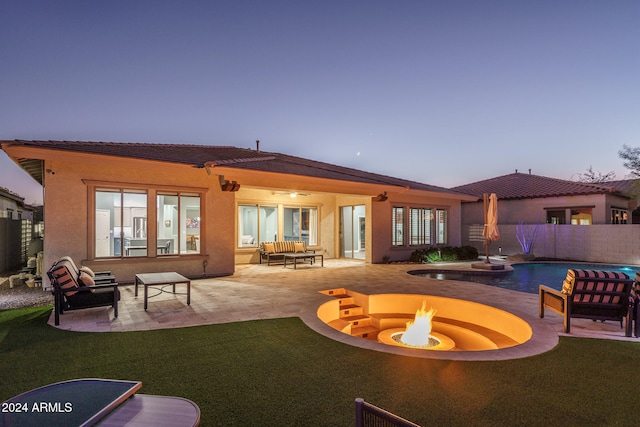 back house at dusk featuring ceiling fan, an outdoor living space with a fire pit, a fenced in pool, and a patio