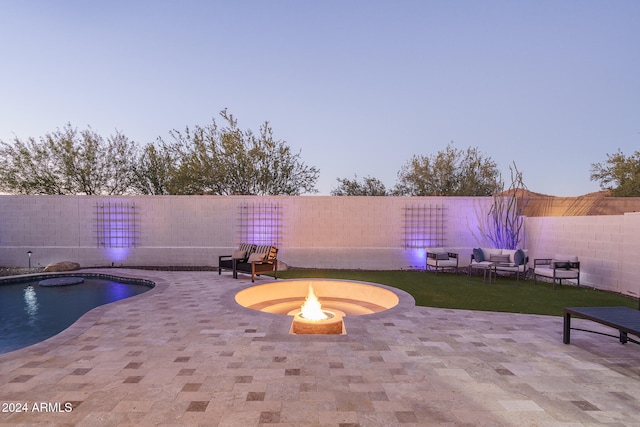 pool at dusk with an outdoor fire pit, a patio, and a yard