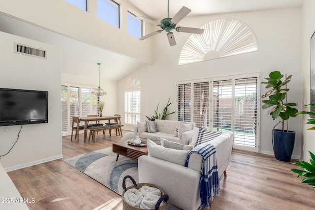 living room with a high ceiling, ceiling fan, and light hardwood / wood-style floors