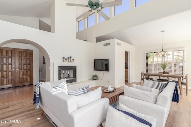 living room featuring high vaulted ceiling, light hardwood / wood-style floors, and ceiling fan