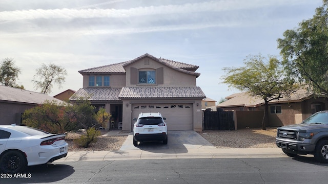 traditional-style house with driveway, a tile roof, fence, and stucco siding