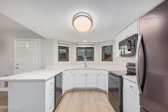 kitchen featuring electric range, freestanding refrigerator, dishwasher, a sink, and a peninsula