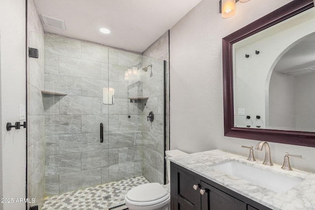 full bathroom featuring toilet, a stall shower, and vanity