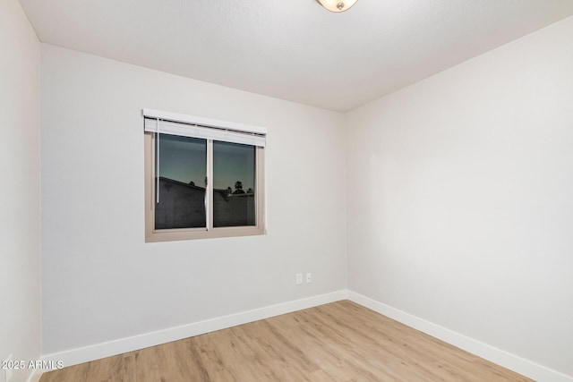unfurnished room with baseboards and wood finished floors