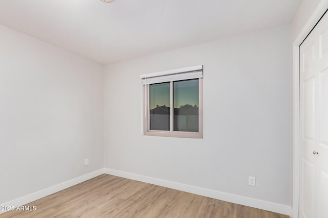 empty room with baseboards and light wood-type flooring