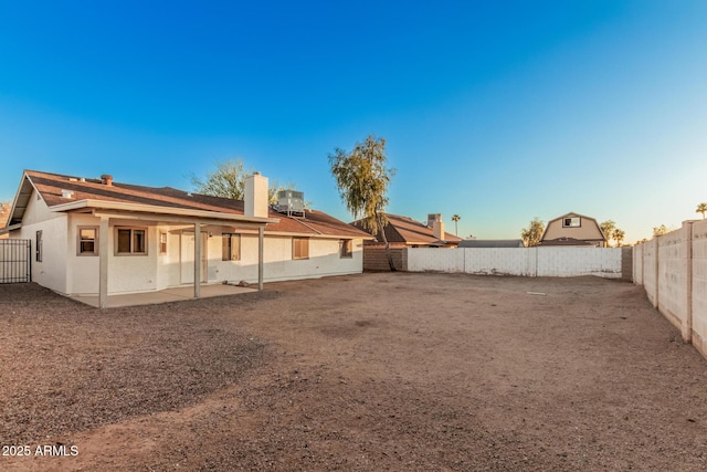 rear view of house featuring a fenced backyard, a patio, stucco siding, and a chimney