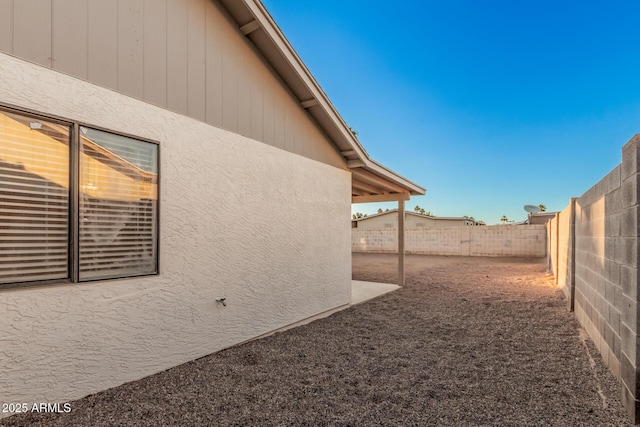 view of side of home featuring a fenced backyard and stucco siding