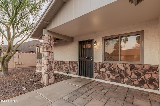 entrance to property with stone siding and stucco siding