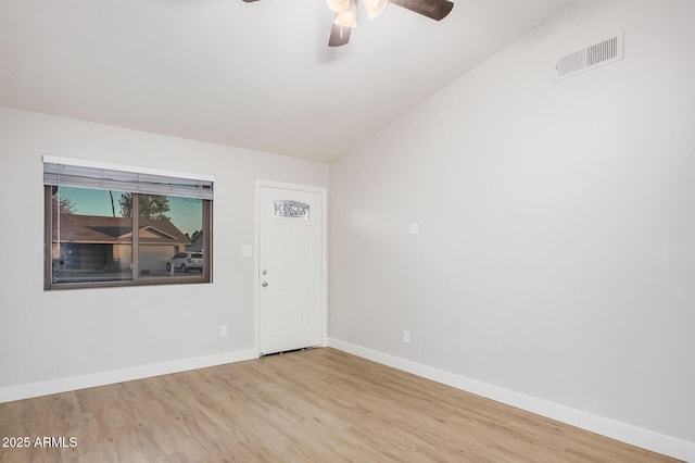 empty room featuring wood finished floors, lofted ceiling, ceiling fan, and baseboards