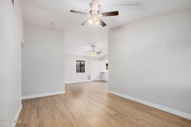 spare room featuring ceiling fan, light wood-style flooring, lofted ceiling, and baseboards