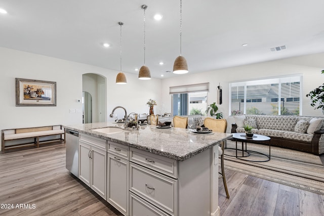 kitchen with a kitchen breakfast bar, an island with sink, dishwasher, decorative light fixtures, and sink