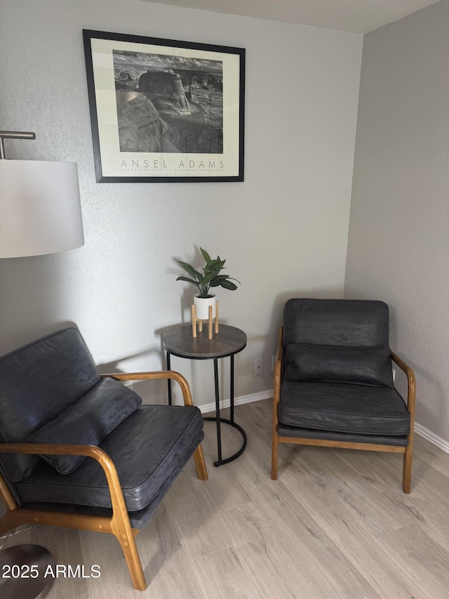 sitting room with baseboards and wood finished floors