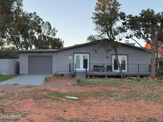 ranch-style house with driveway, french doors, stucco siding, and a garage