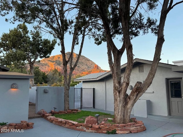 view of home's exterior featuring a mountain view, fence, stucco siding, and a gate