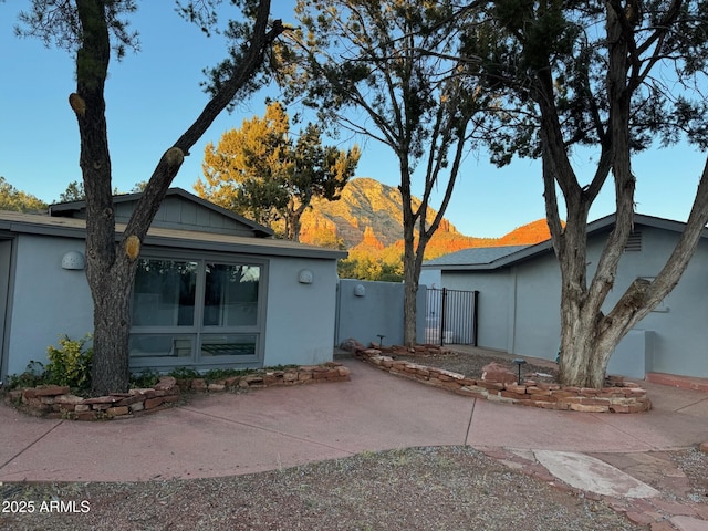view of front of house featuring a patio, a mountain view, stucco siding, and fence