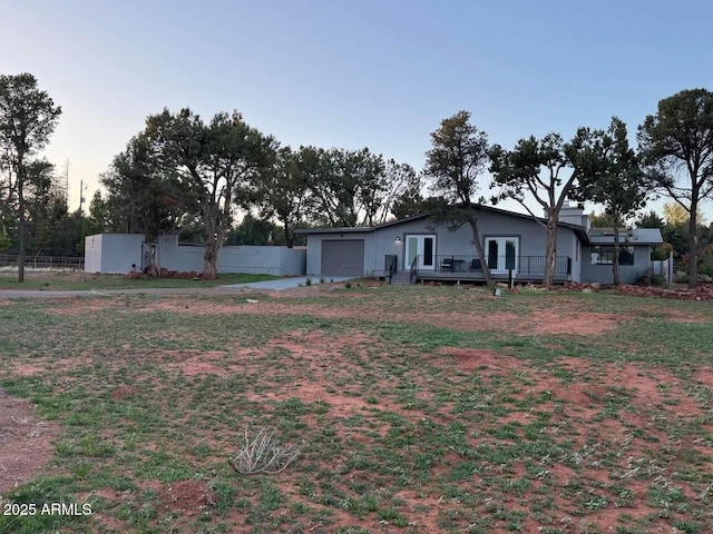 view of yard featuring fence, a deck, french doors, and an attached garage