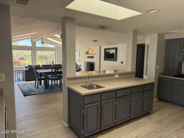 kitchen featuring open floor plan, light wood-style floors, light countertops, and a sink