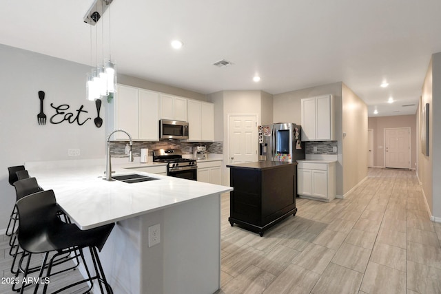 12731 W Myrtle Ave, Glendale, AZ 85307 - kitchen with appliances with stainless steel finishes, decorative backsplash, a peninsula, a kitchen bar, and white cabinets