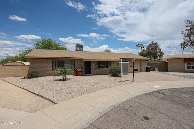 ranch-style home with concrete driveway, brick siding, fence, and a garage
