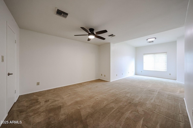 spare room featuring light colored carpet, ceiling fan, and baseboards