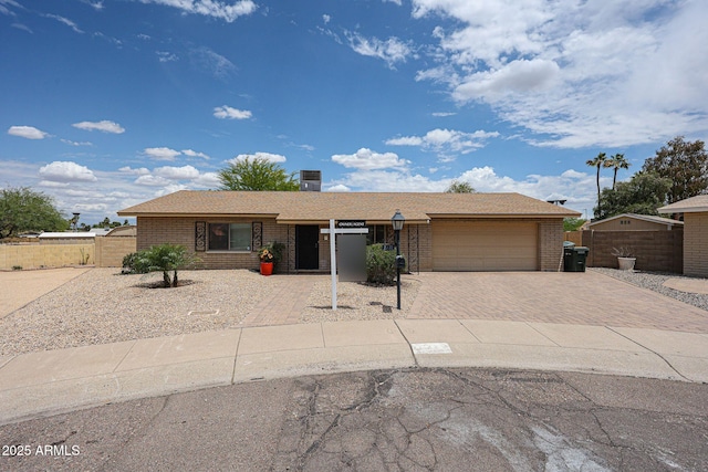 ranch-style house with brick siding, decorative driveway, an attached garage, and fence