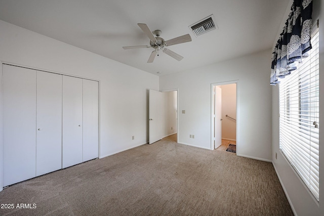 unfurnished bedroom with carpet, a closet, ceiling fan, ensuite bathroom, and baseboards