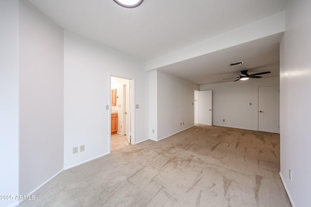 spare room featuring light colored carpet, ceiling fan, and baseboards